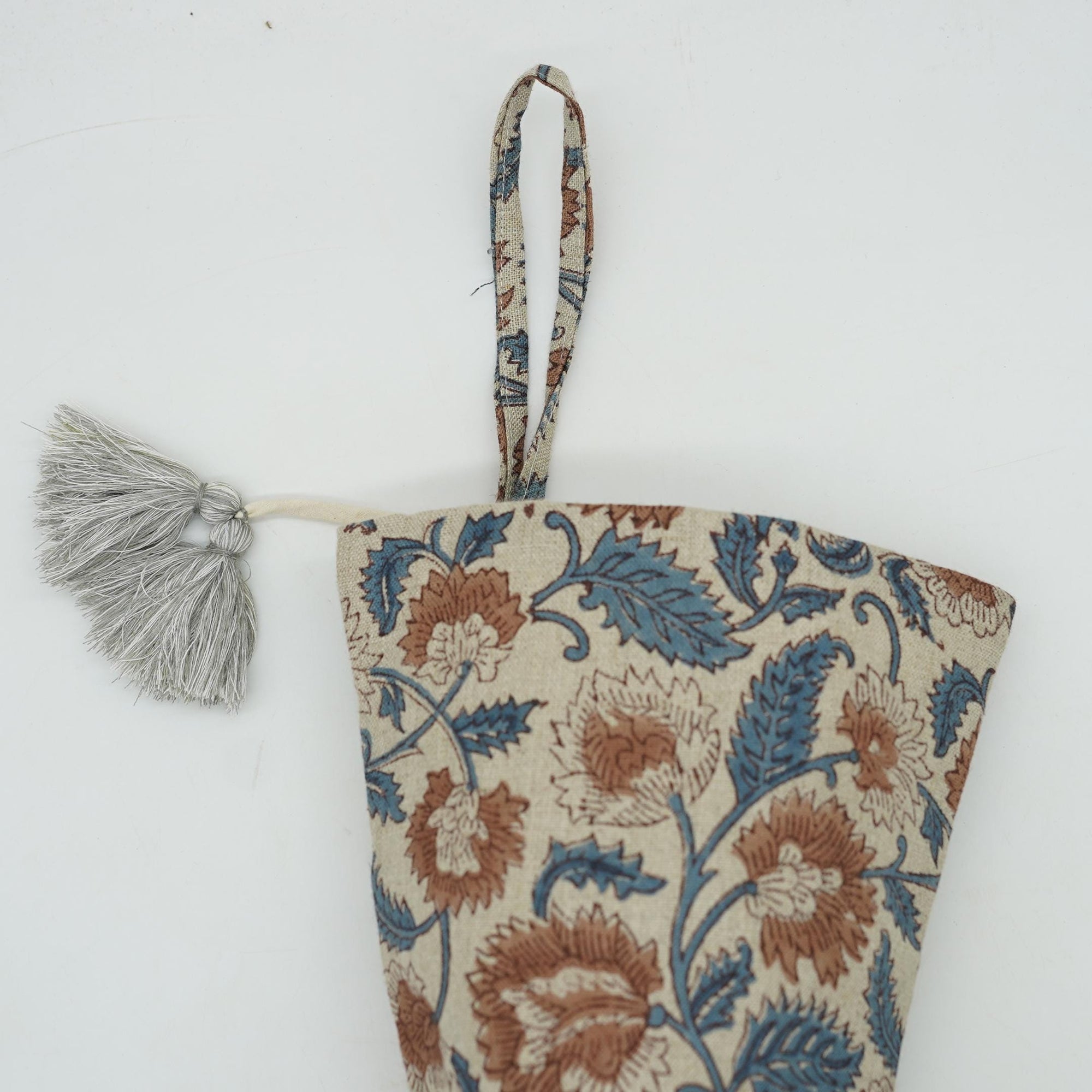 Floral patterned fabric pouch with tassel on white background.