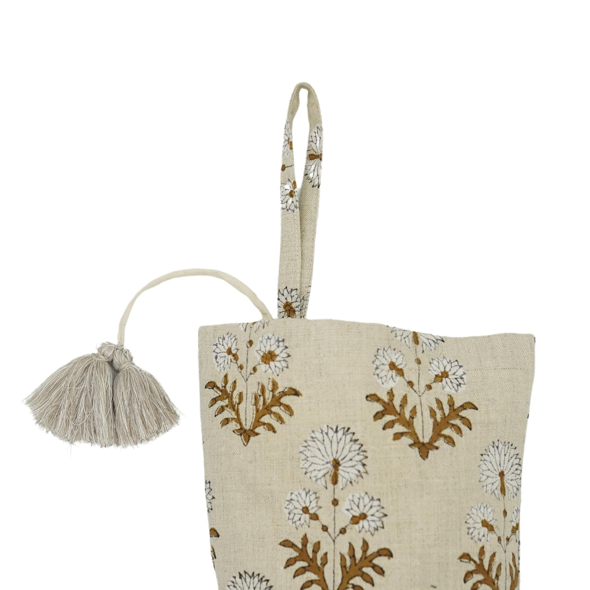 Beige tote bag with floral patterns and tassel on white background.