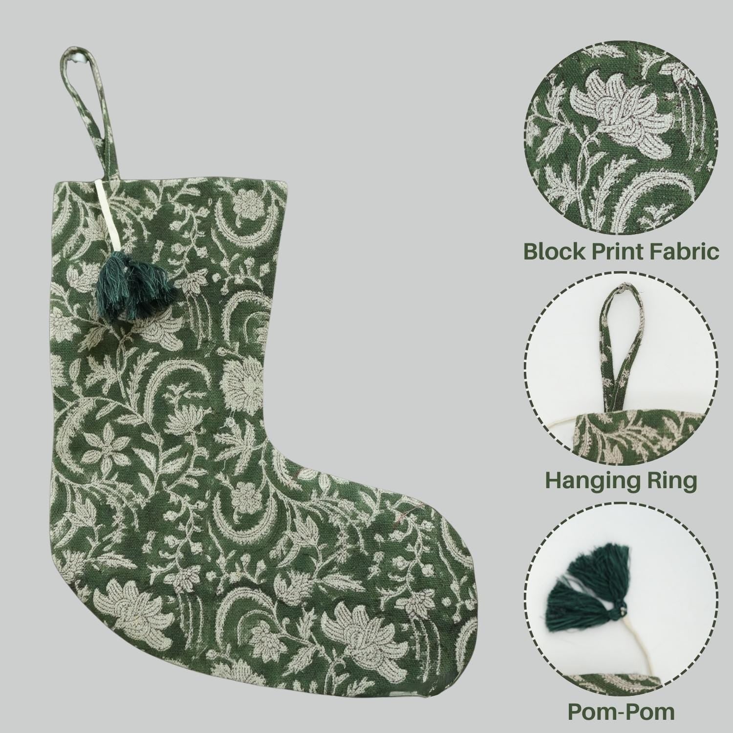 Green floral stocking with pom-pom and hanging ring on gray background.