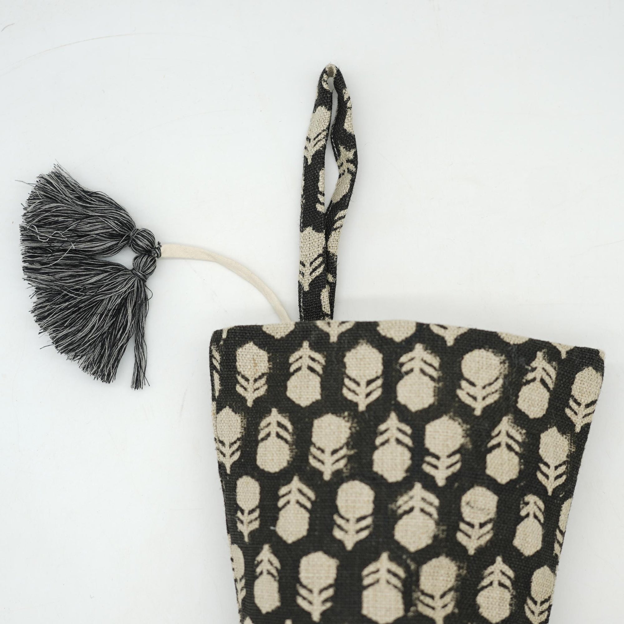 Black stocking fabric pouch with leaf pattern and tassel.