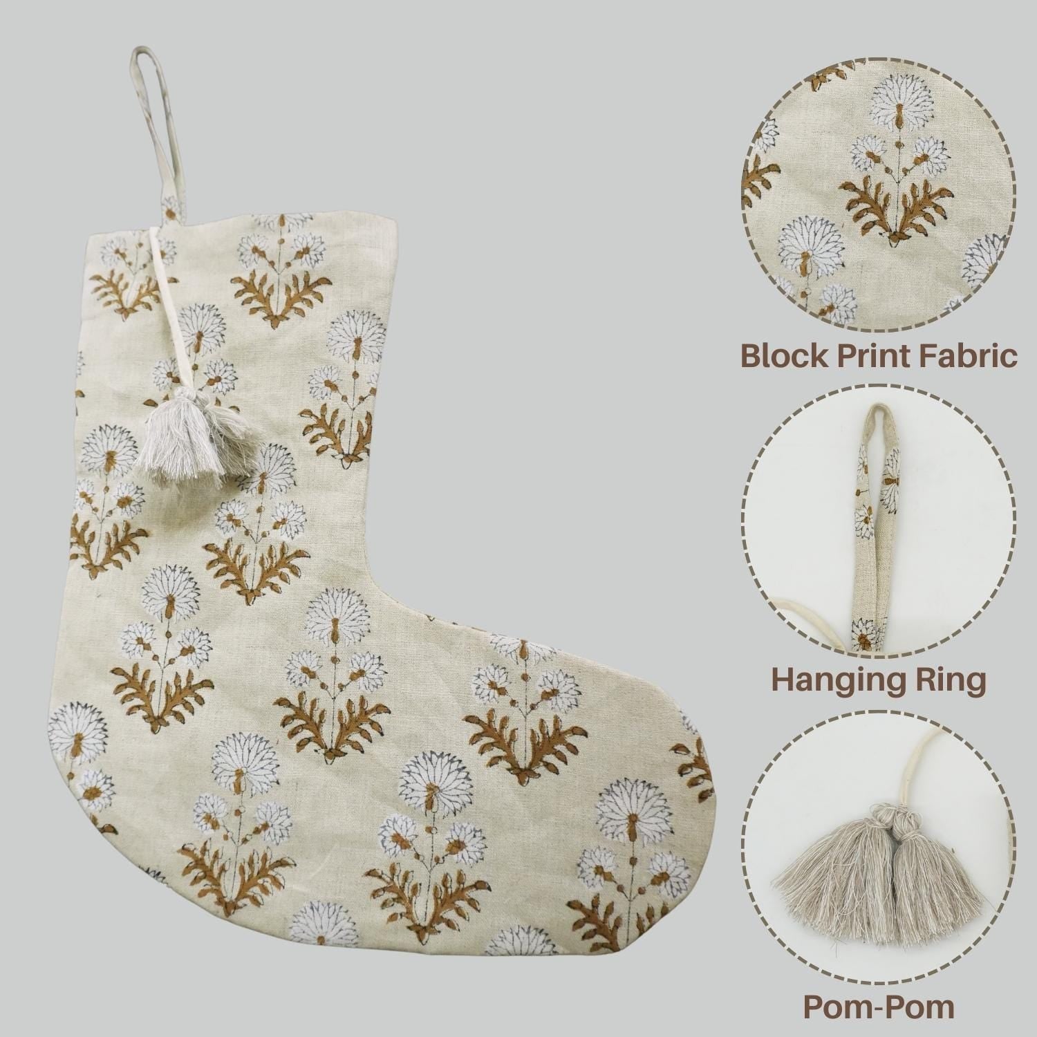 Decorative Christmas stocking with block print, pom-pom, and hanging ring on gray background.