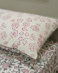Floral patterned pillow and bed sheets on a bed.