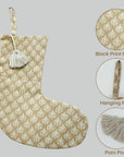 Beige Christmas stocking with block print, pom-pom, and hanging ring on gray background.