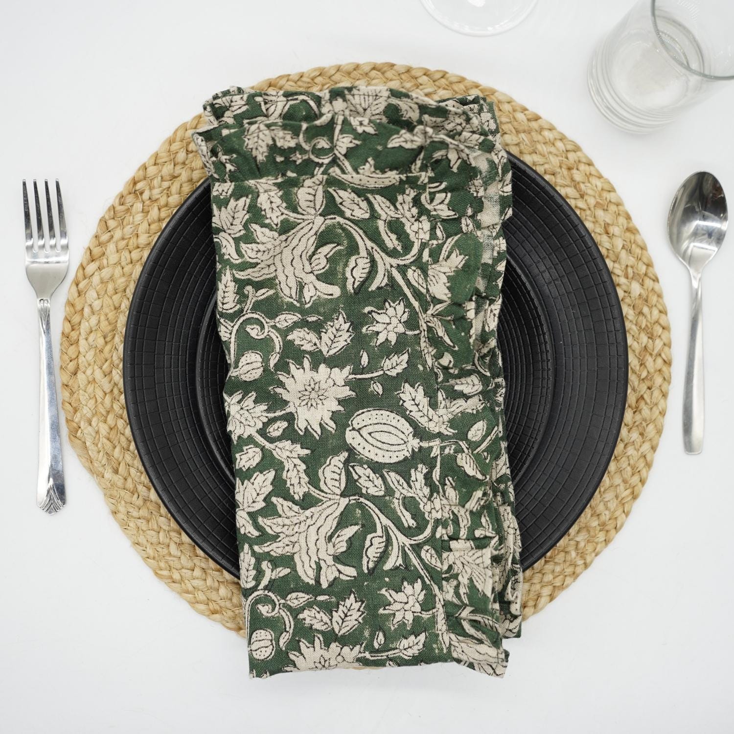 Green block print frill napkin on a warm dining table setting.