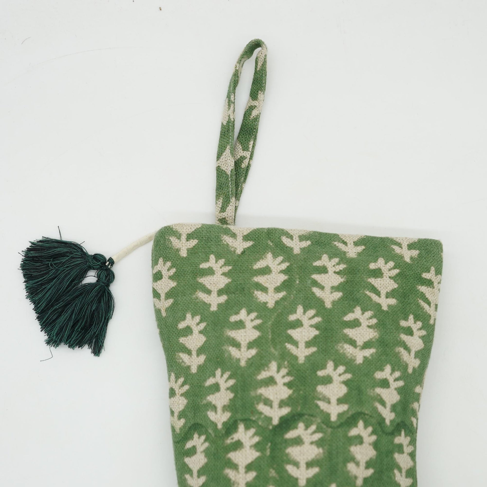 Green and white patterned pouch with tassel on white background.