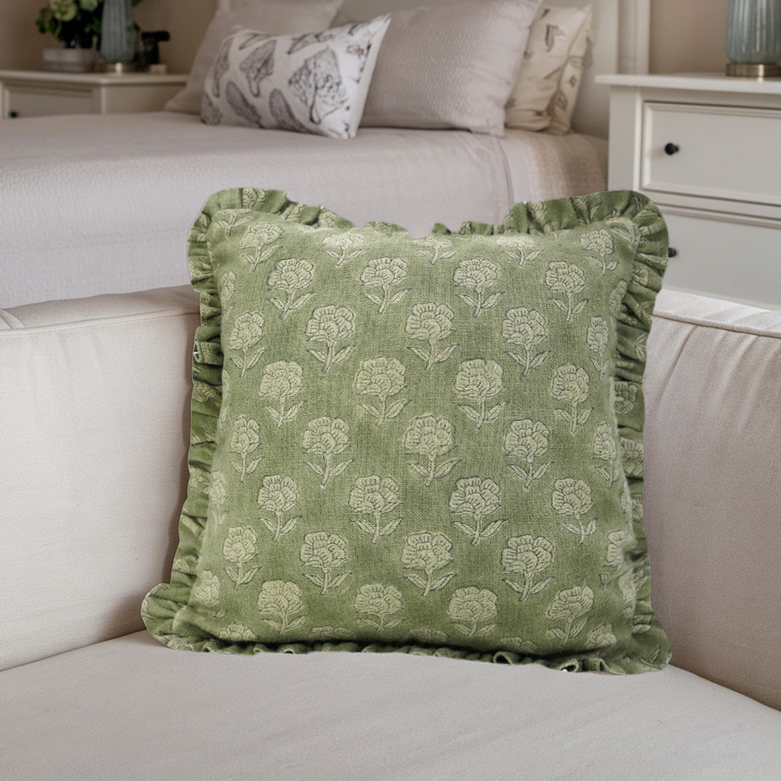 Beige sofa with green floral frill linen pillow covers in a cozy bedroom.