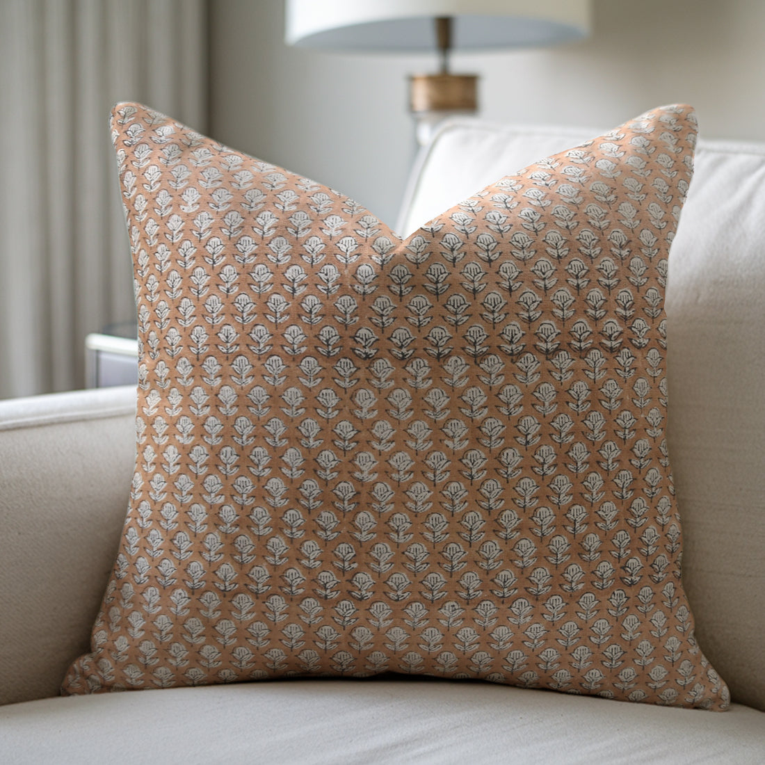 Patterned pillow on a sofa with a blurred lamp in the background