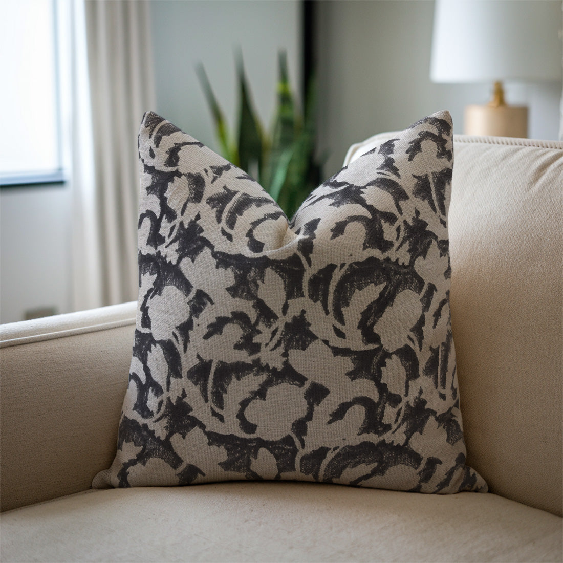 Decorative pillow with black floral pattern on a beige sofa