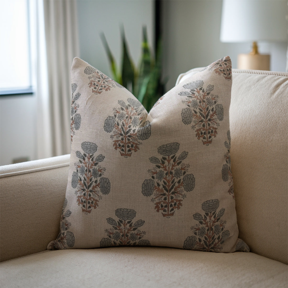 Grey linen pillows with floral pattern on a beige sofa