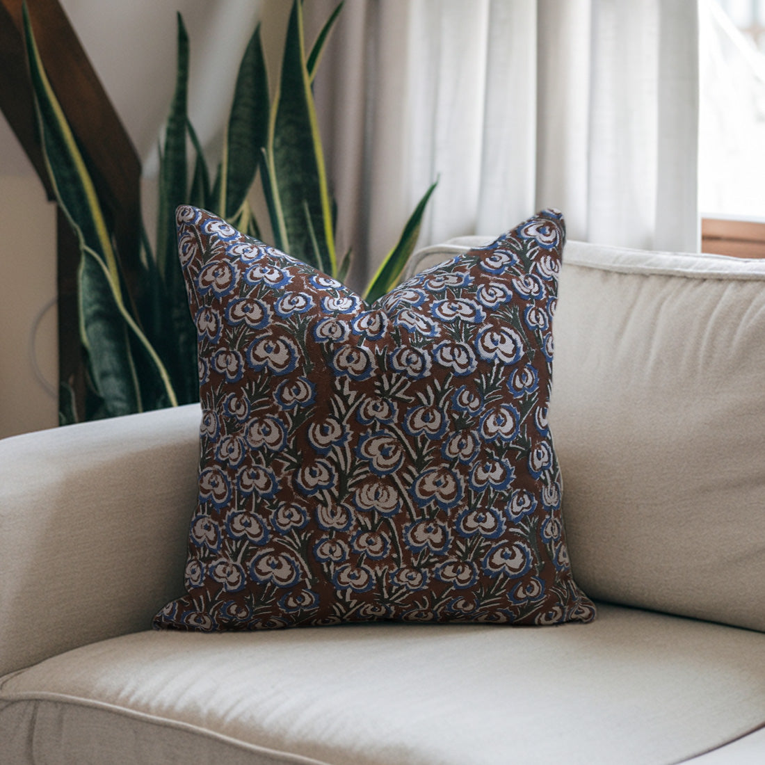Large black  pillow with floral pattern on a beige sofa 