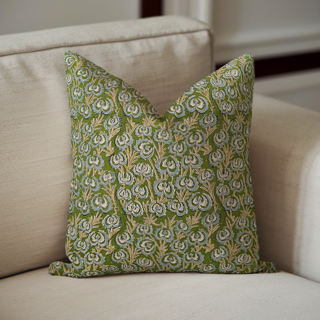 Green floral patterned pillow on a beige sofa