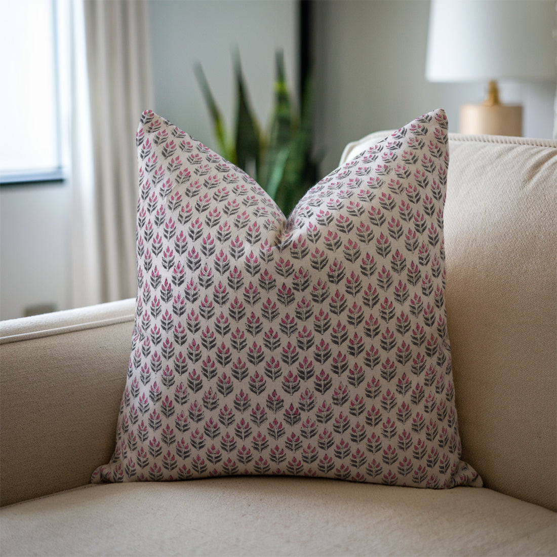 Floral patterned pillow on a beige sofa with a neutral background
