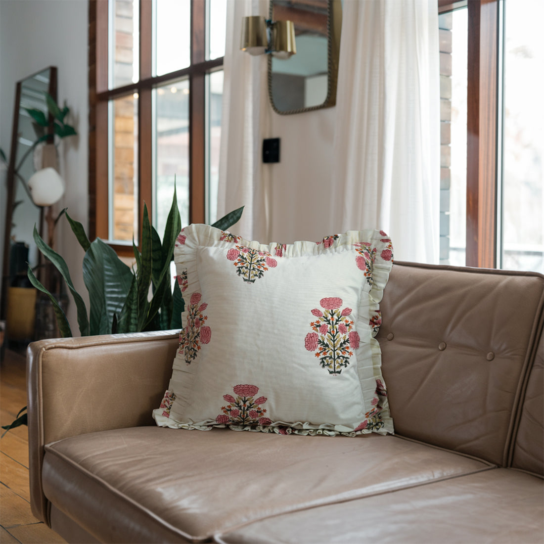 Beige sofa with bright pink floral linen pillow covers in a sunny living room.