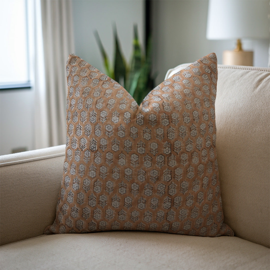Patterned pillow on a beige sofa with a neutral background