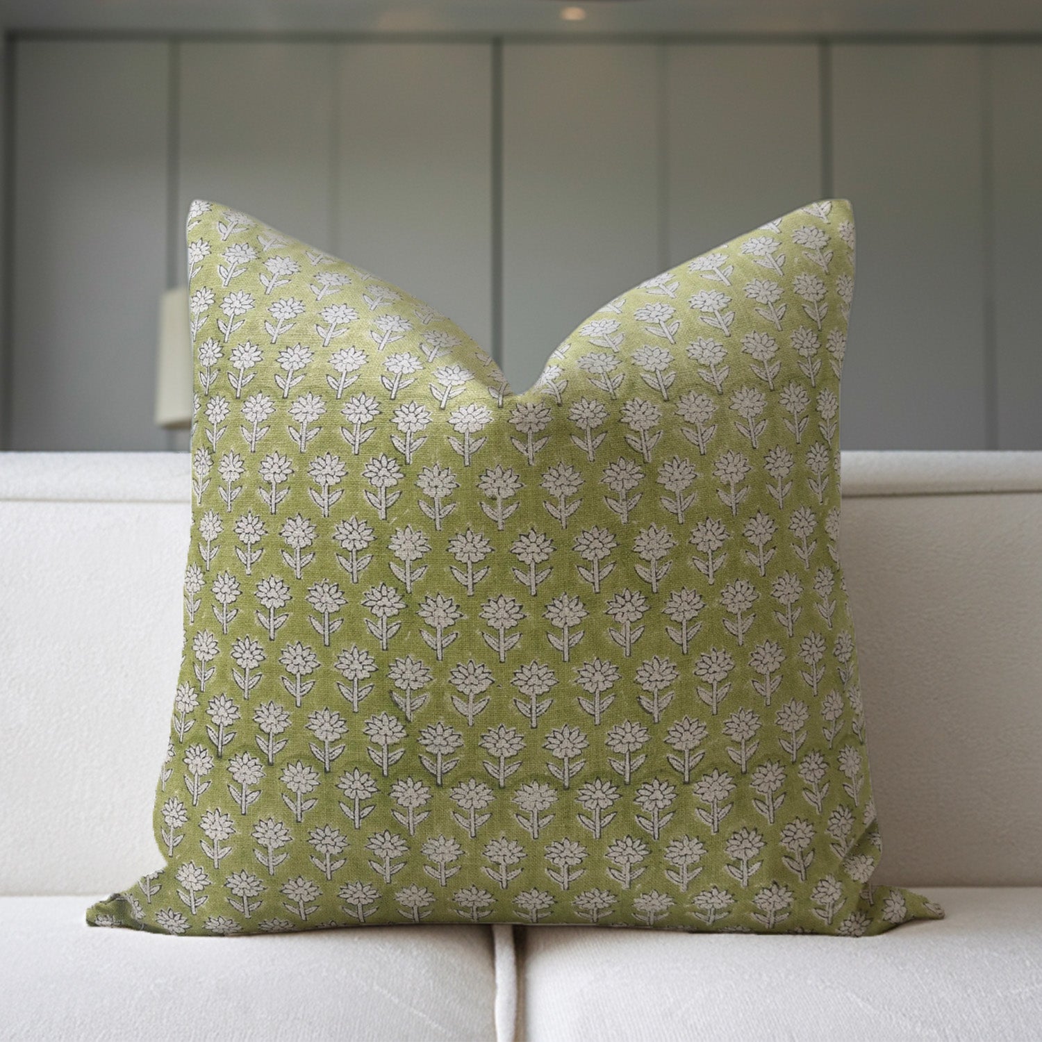 Green pillow with white floral pattern on a white sofa