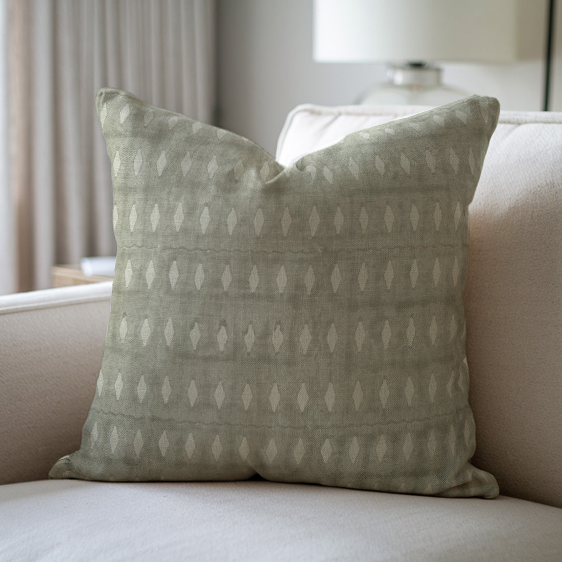 Patterned green pillow on a beige sofa with a neutral background