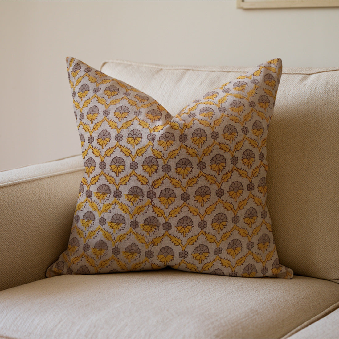 Decorative pillow with a yellow and brown pattern on a beige sofa.
