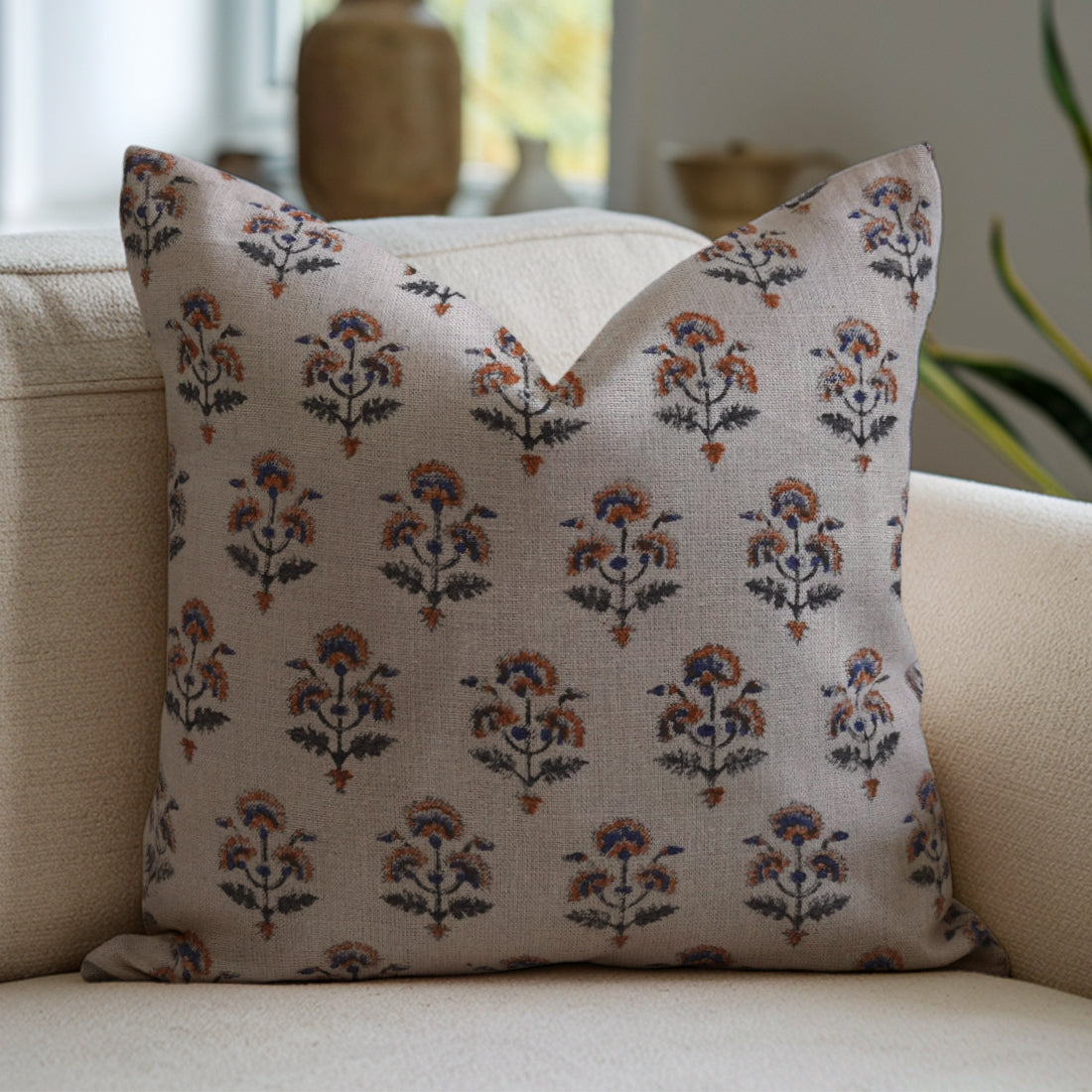 Chic beige couch accented with a colorful decorative pillow in a floral pattern.