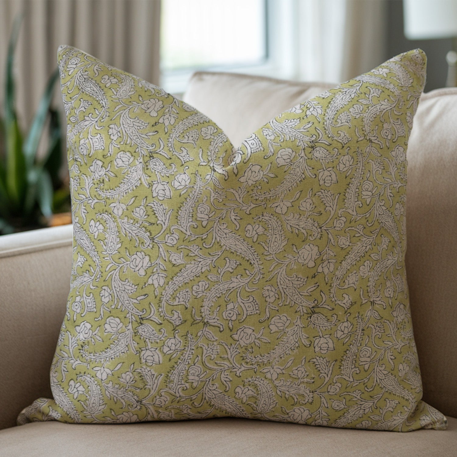 Green pillow with floral pattern on a beige sofa