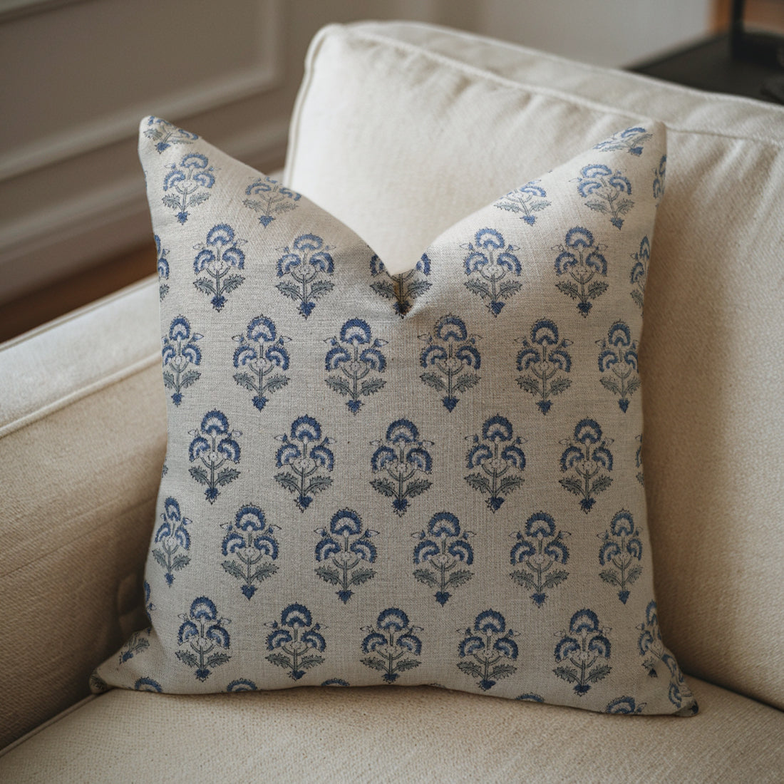 Decorative pillow with blue floral pattern on a beige sofa