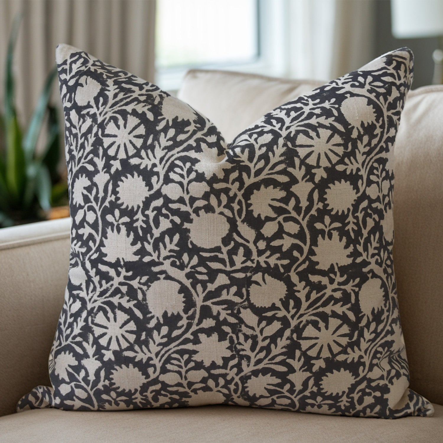 Decorative black pillow with floral pattern on a beige sofa