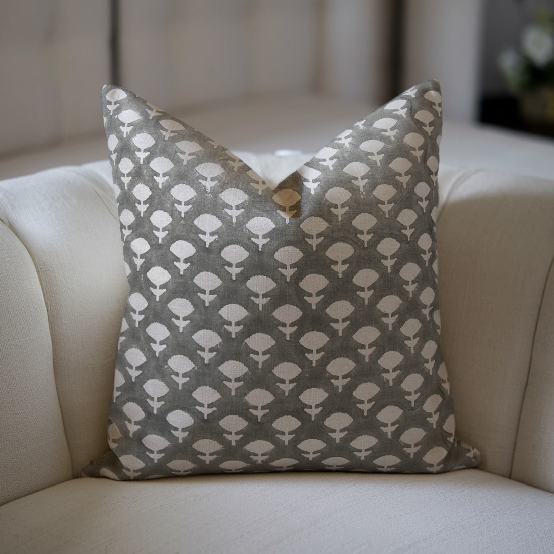 grey pillow with a floral pattern on a beige sofa