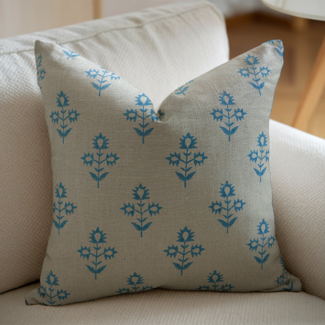 Decorative pillow with blue floral pattern on a beige couch