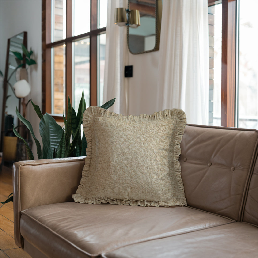 Beige couch brightened with a cozy frill linen pillow cover, surrounded by sunlight and lush indoor plants.