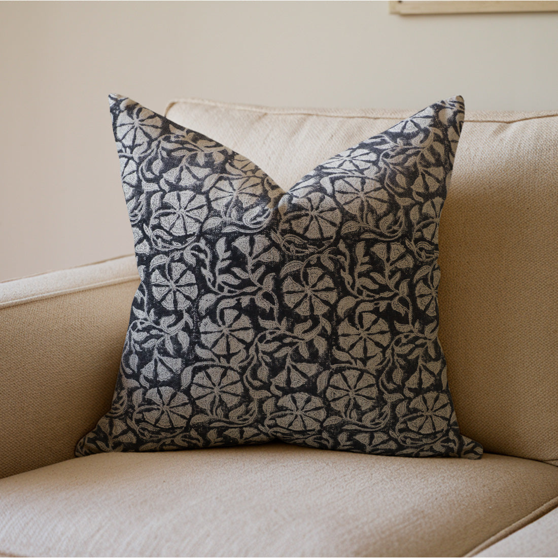 Decorative pillow with a black and white pattern on a beige couch.