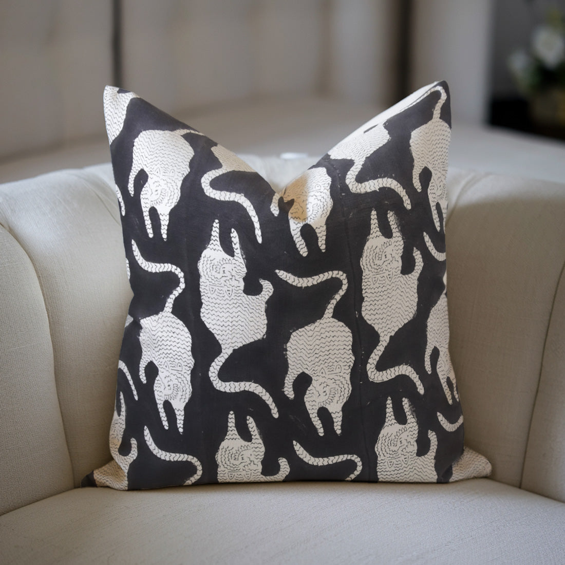 Black floral pillow with elephant pattern on a beige sofa