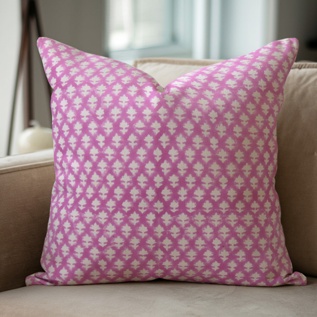 Pink and white patterned pillow on a beige sofa