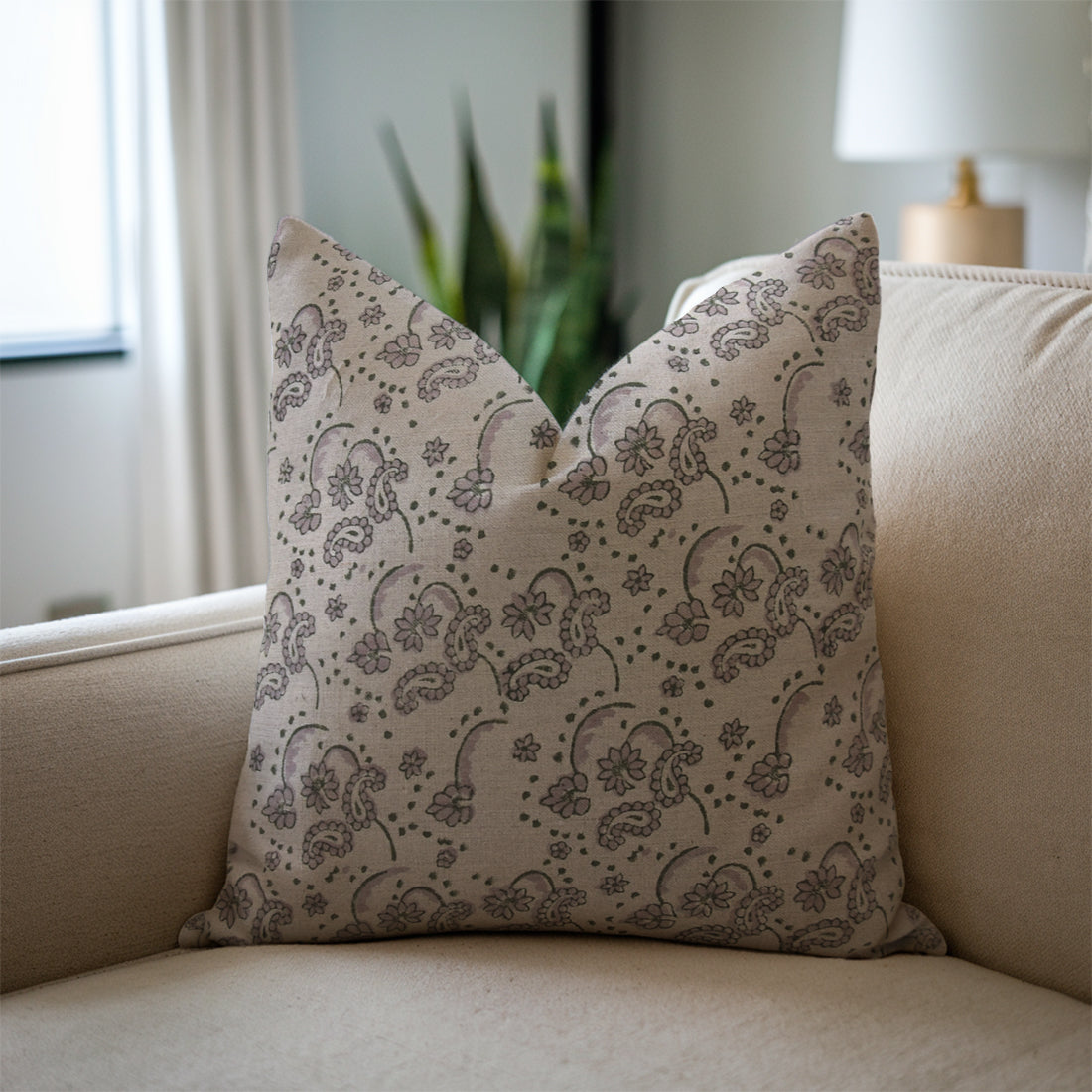 Decorative pillow with a floral pattern on a beige sofa in a living room setting, styled with bohemian pillow cases.