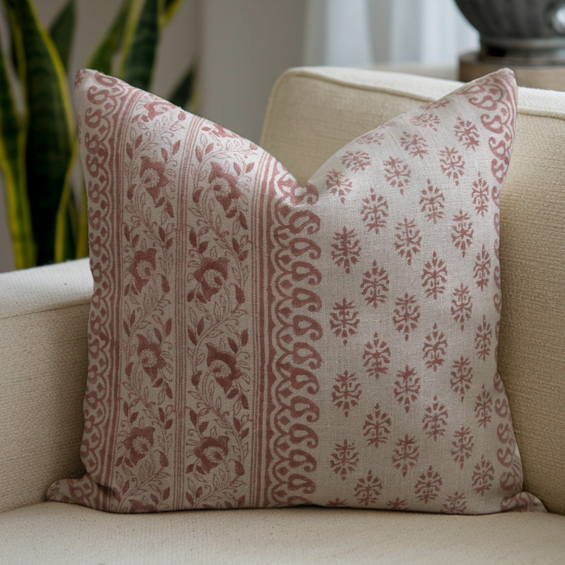 Decorative pillow with a red and beige pattern on a beige sofa.