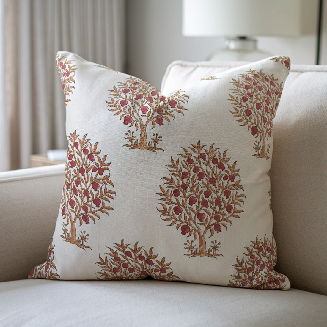 White and red pillow with tree pattern on a beige sofa