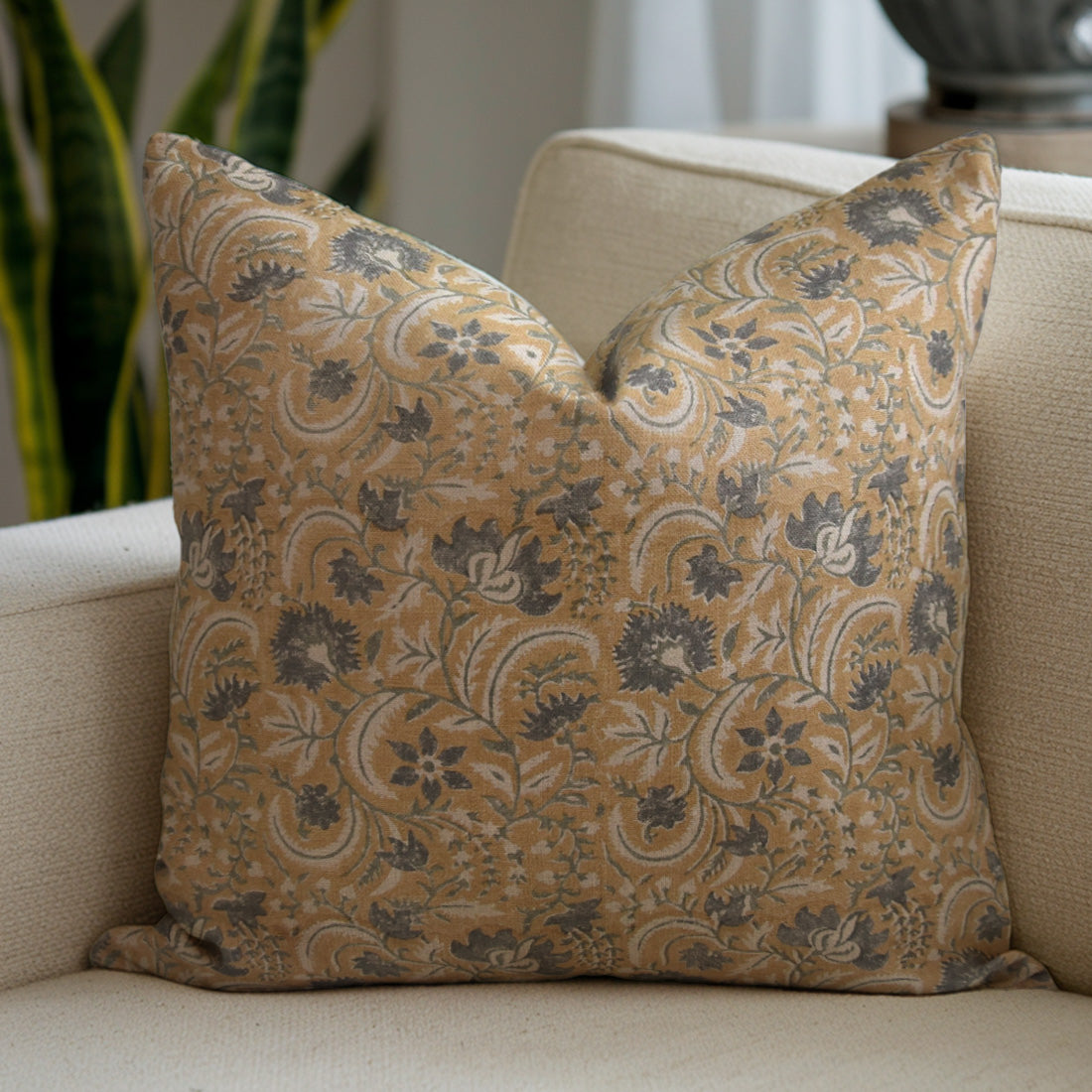 Floral patterned pillow on a beige sofa with a blurred background