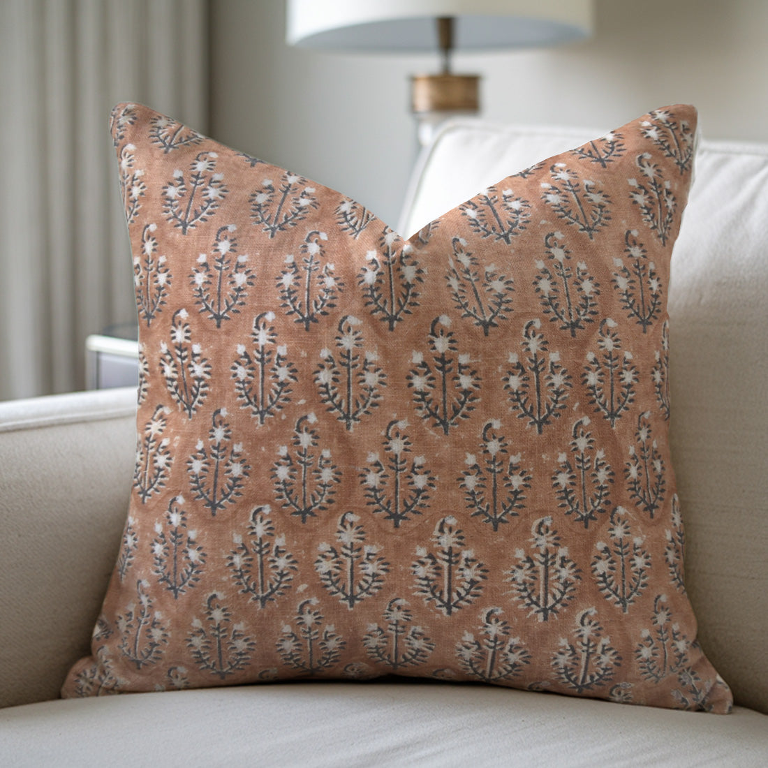 Patterned pillow on a beige sofa with a blurred lamp in the background