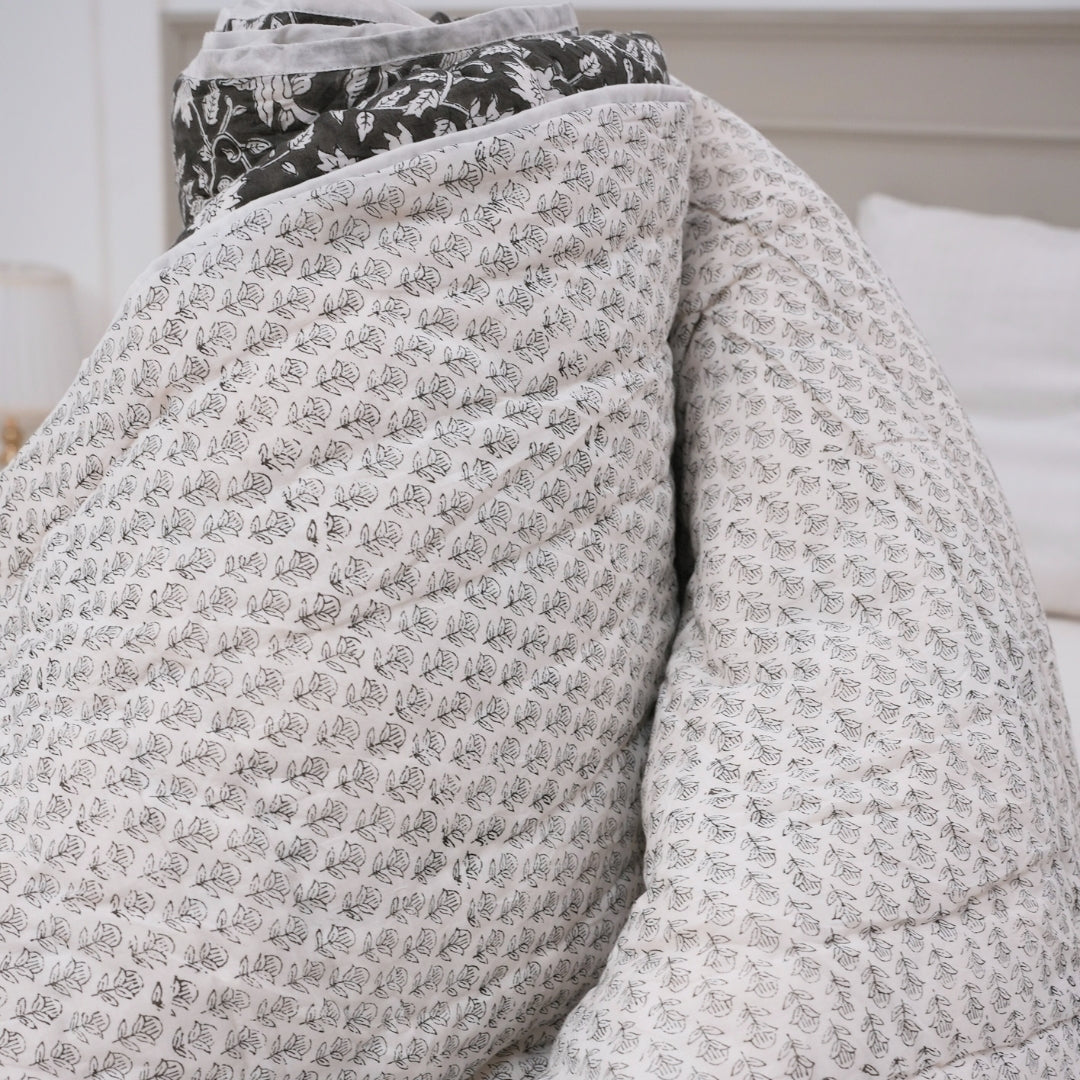 Floral-patterned quilt draped over a bed in a bedroom setting