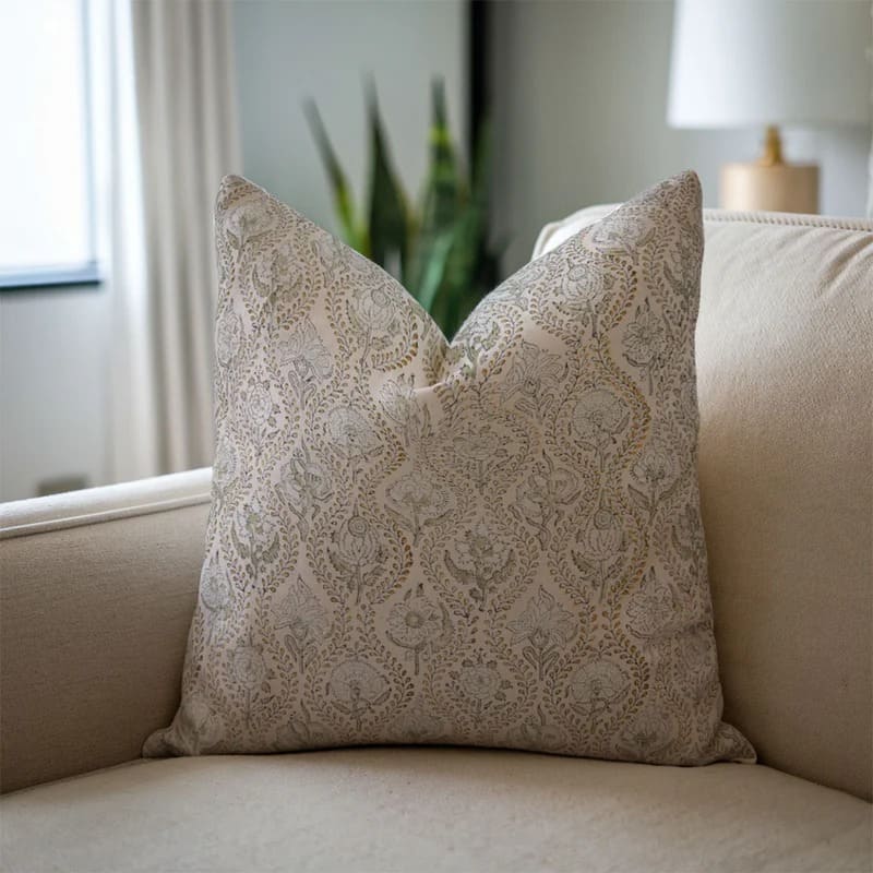 Decorative pillow with lace pattern on a beige sofa in a living room setting.