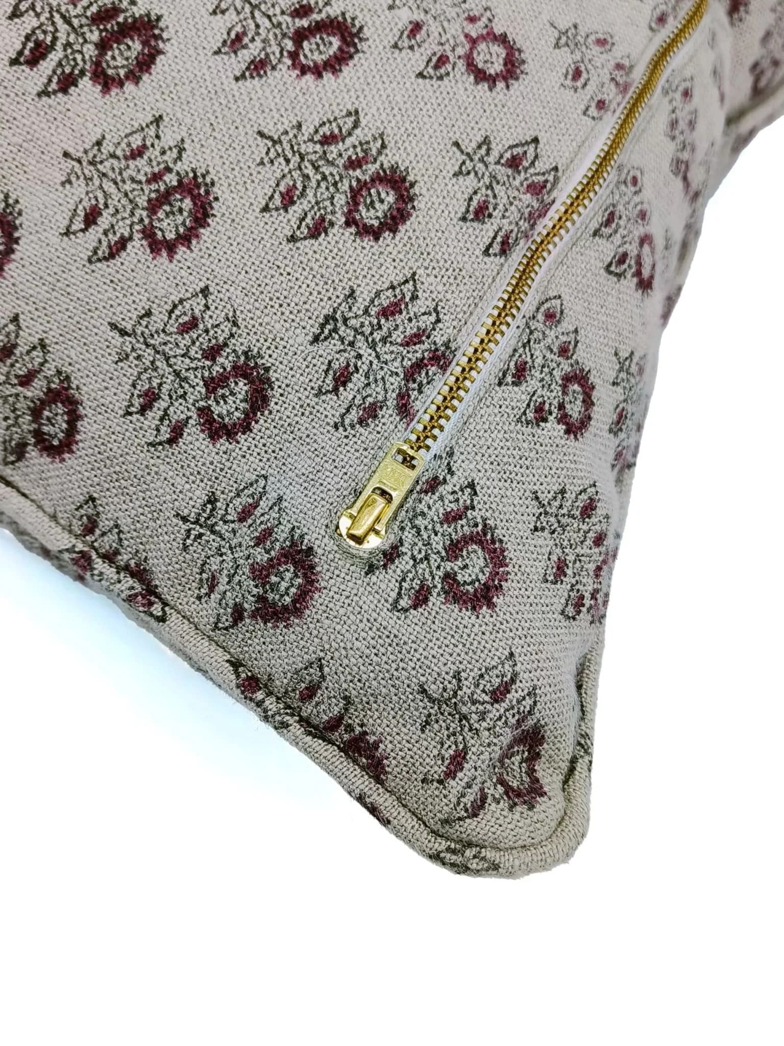 Floral patterned cushion with a gold zipper on a white background