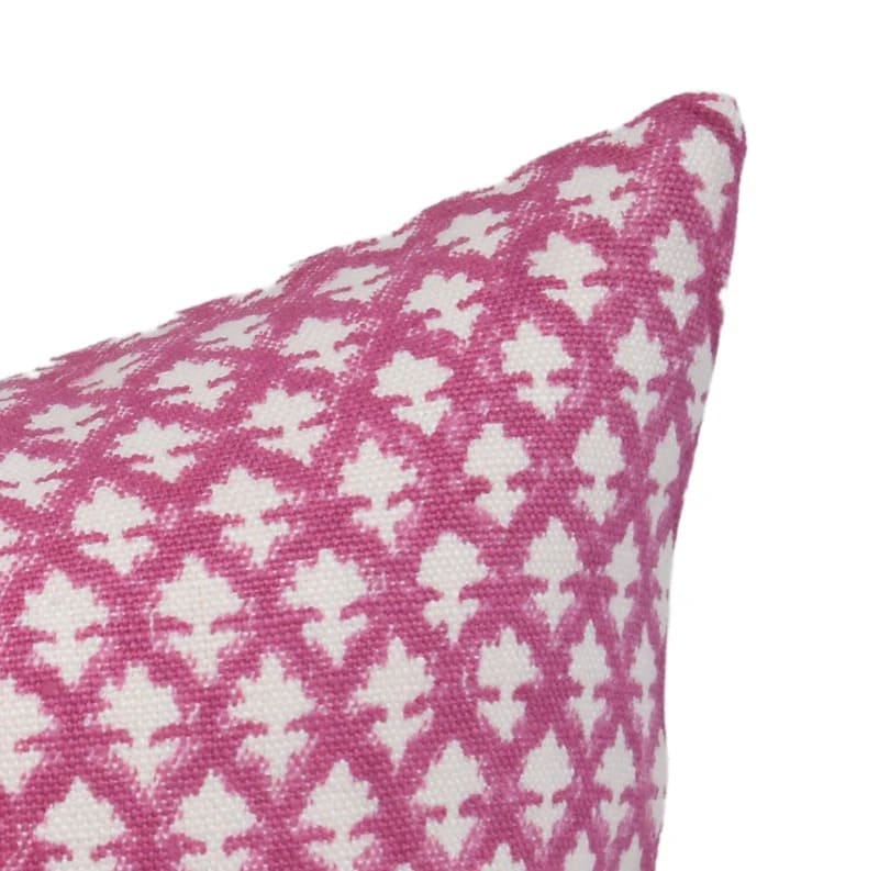 Pink and white patterned pillow on a white 