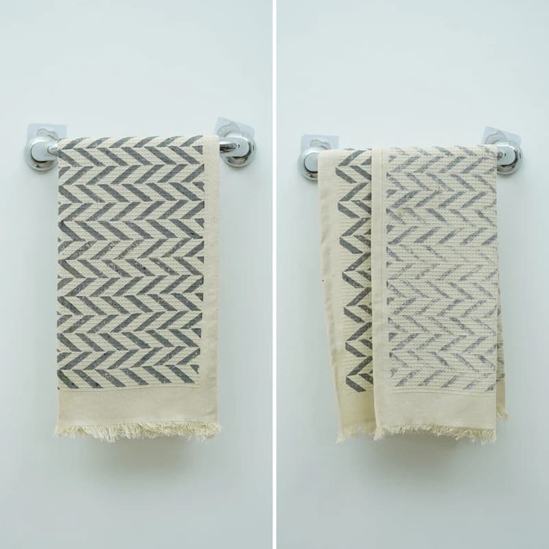 Green patterned towel rolled on bathroom shelf