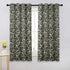 Decorative curtains with a floral pattern on a window with a white wall background.