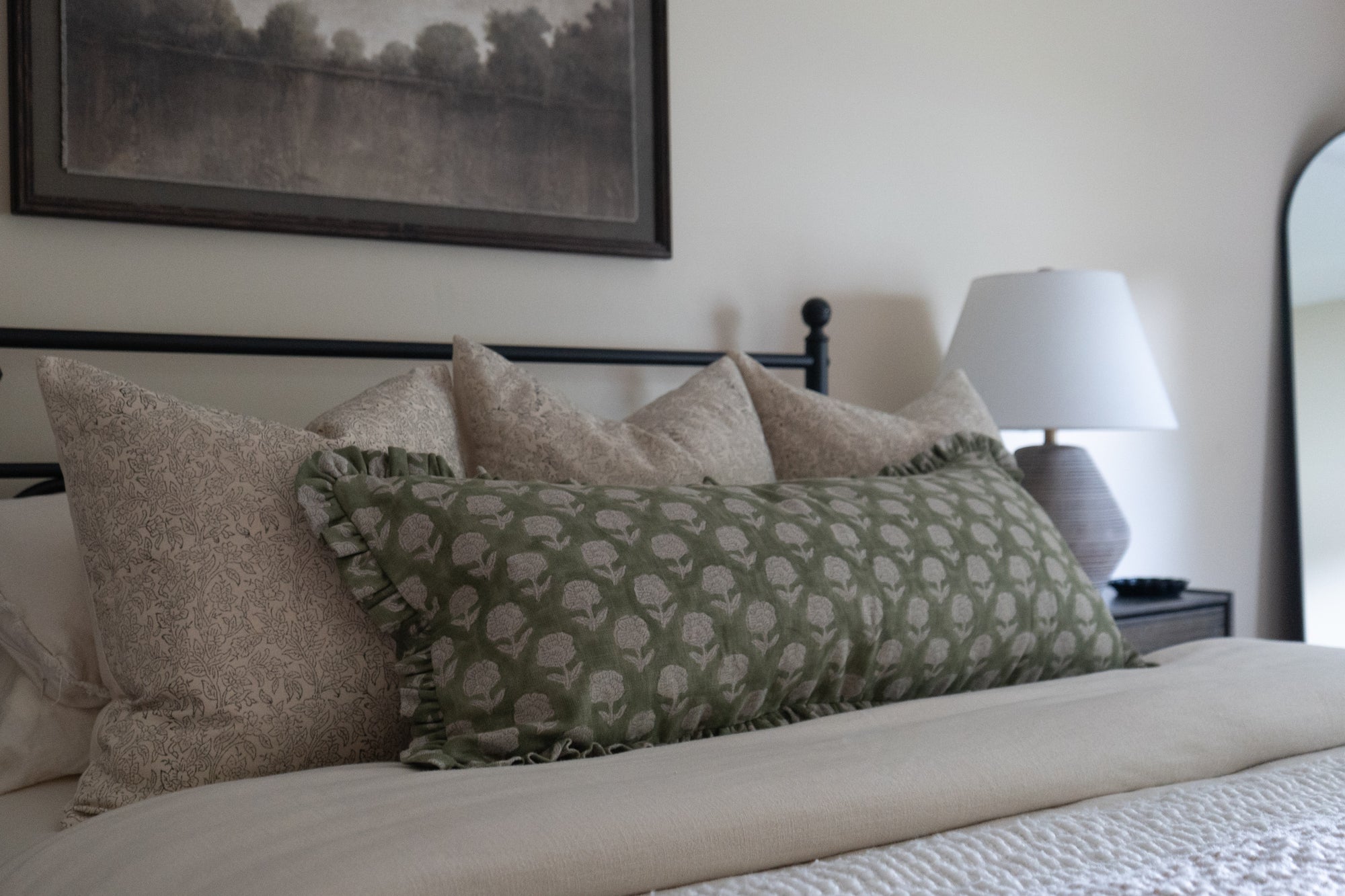 Bed with decorative pillows and lamp in cozy bedroom setting.