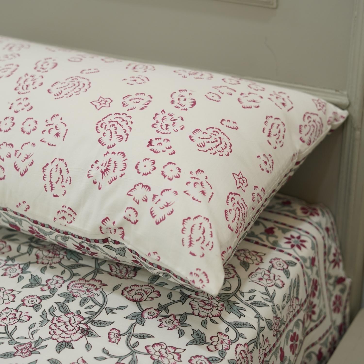 Floral patterned pillow and bed sheets on a bed.
