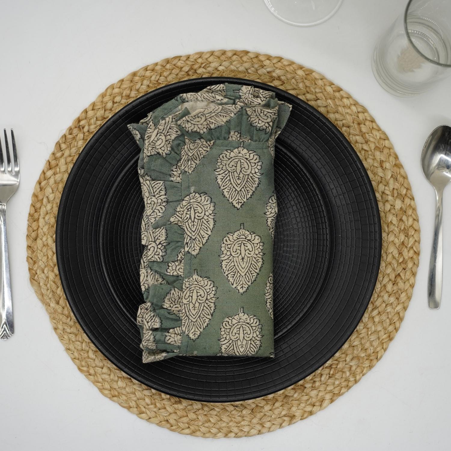 Green block print frill napkin styled on a woven placemat.