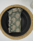 Green block print frill napkin styled on a woven placemat.