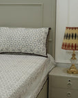 Bedsheet with patterned bedding and pillow, nightstand with lamp in a bedroom setting