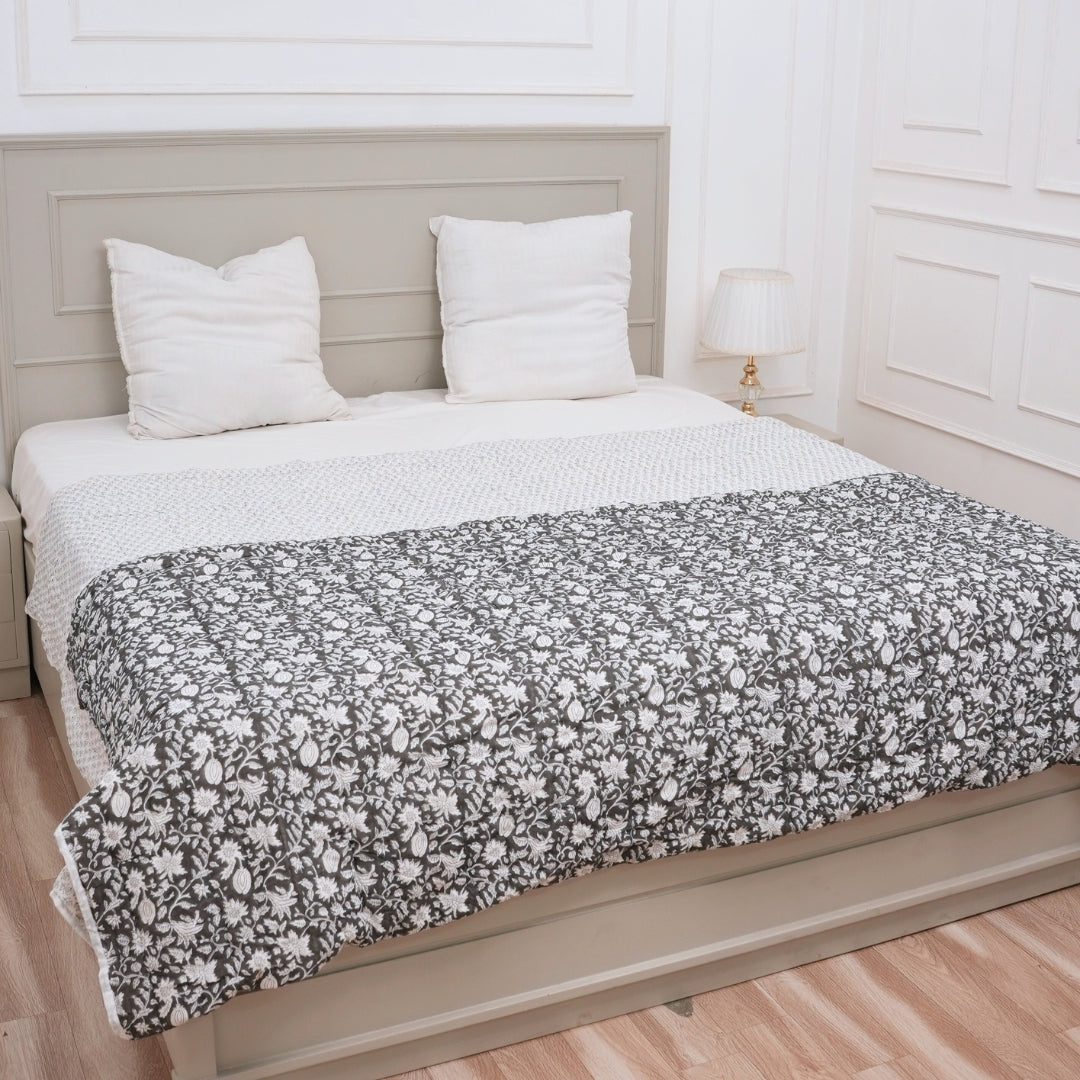 Bed with floral-patterned comforter and white pillows in a bedroom setting.
